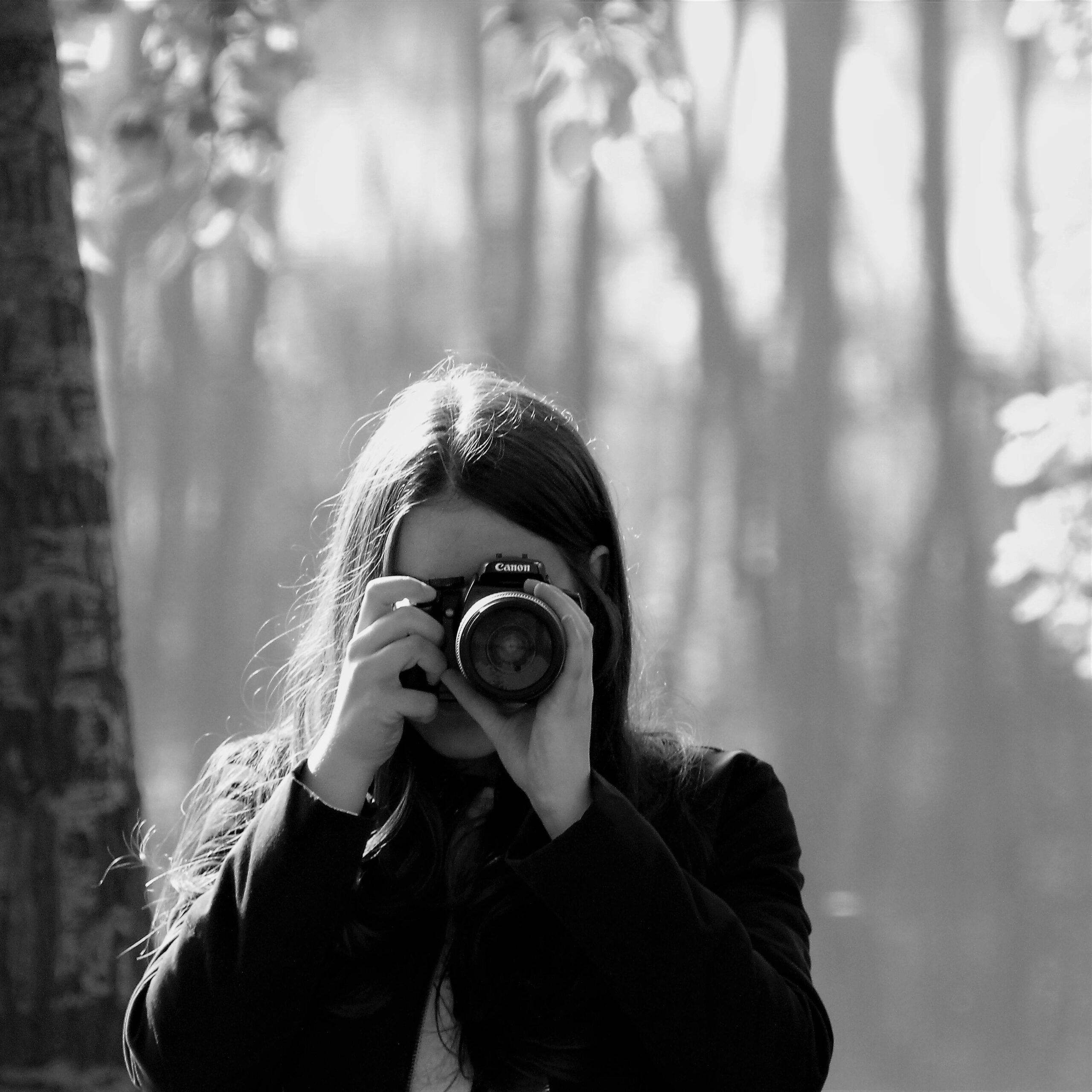 Artistic black and white portrait of a female photographer capturing nature.